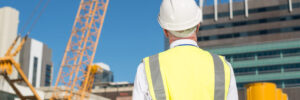 Back view of construction engineer in hardhat looking at building